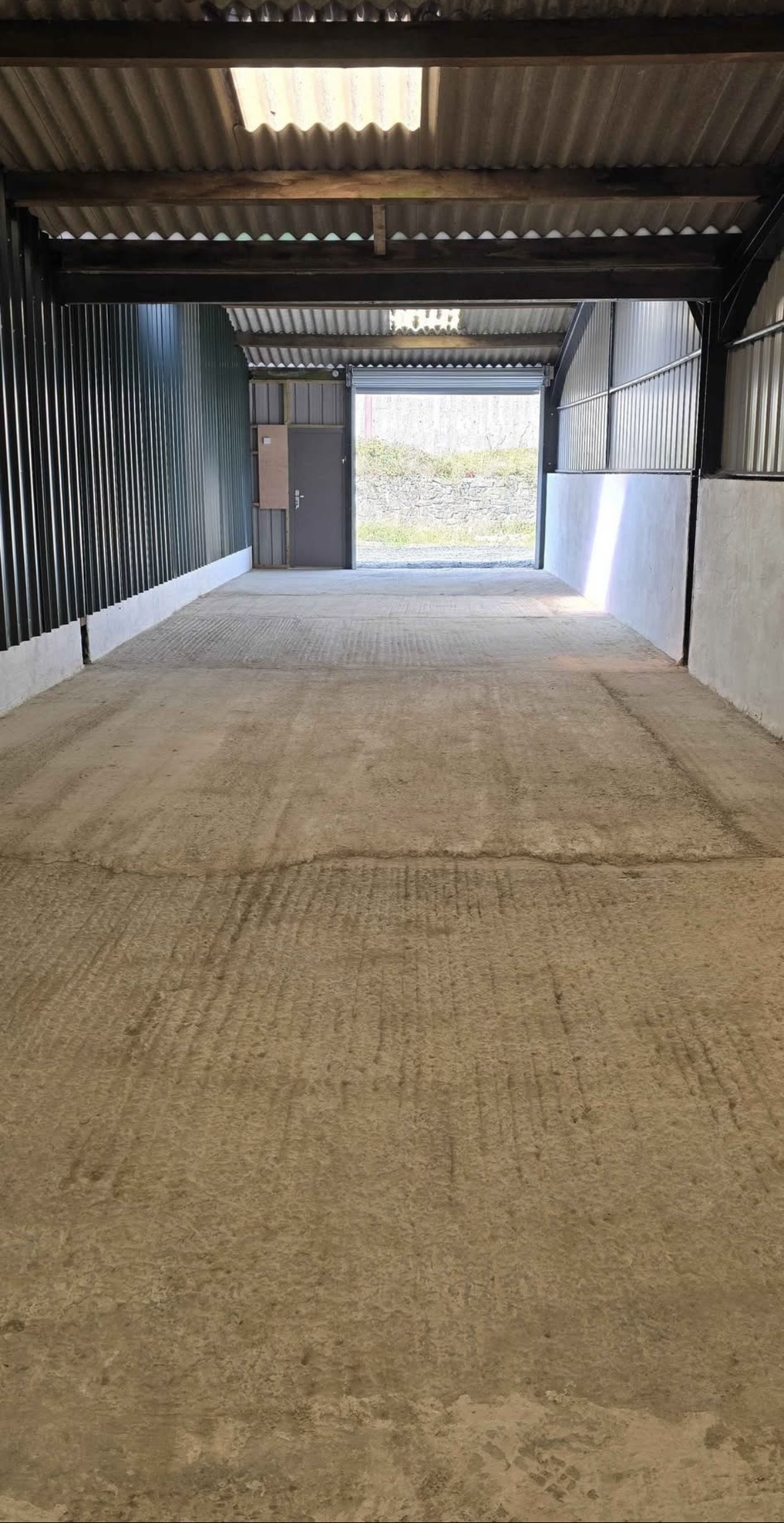 View from inside a storage unit towards the open roller shutter and pedestrian door