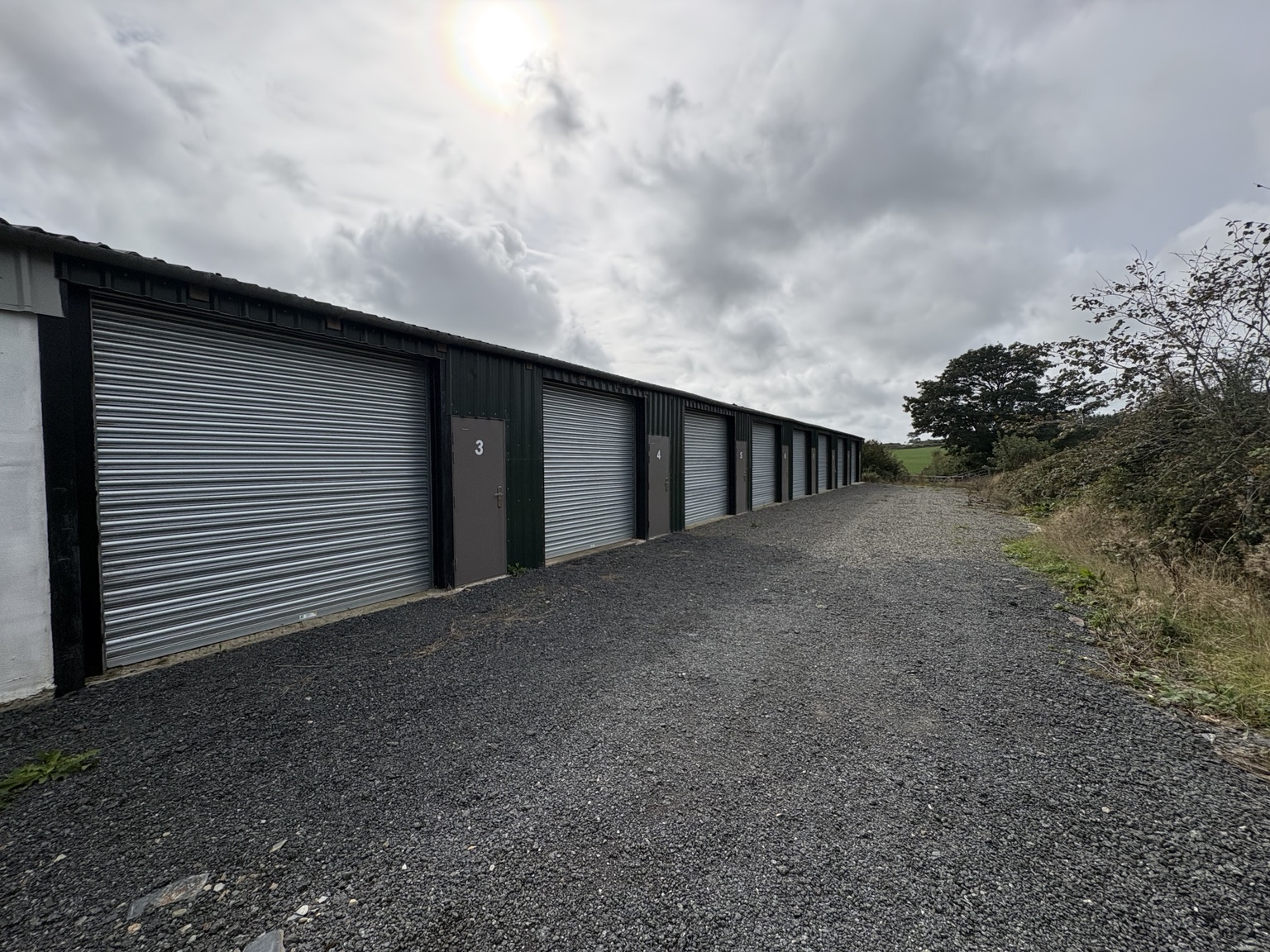 Row of Summerton storage units with closed roller shutters beside the gravel area