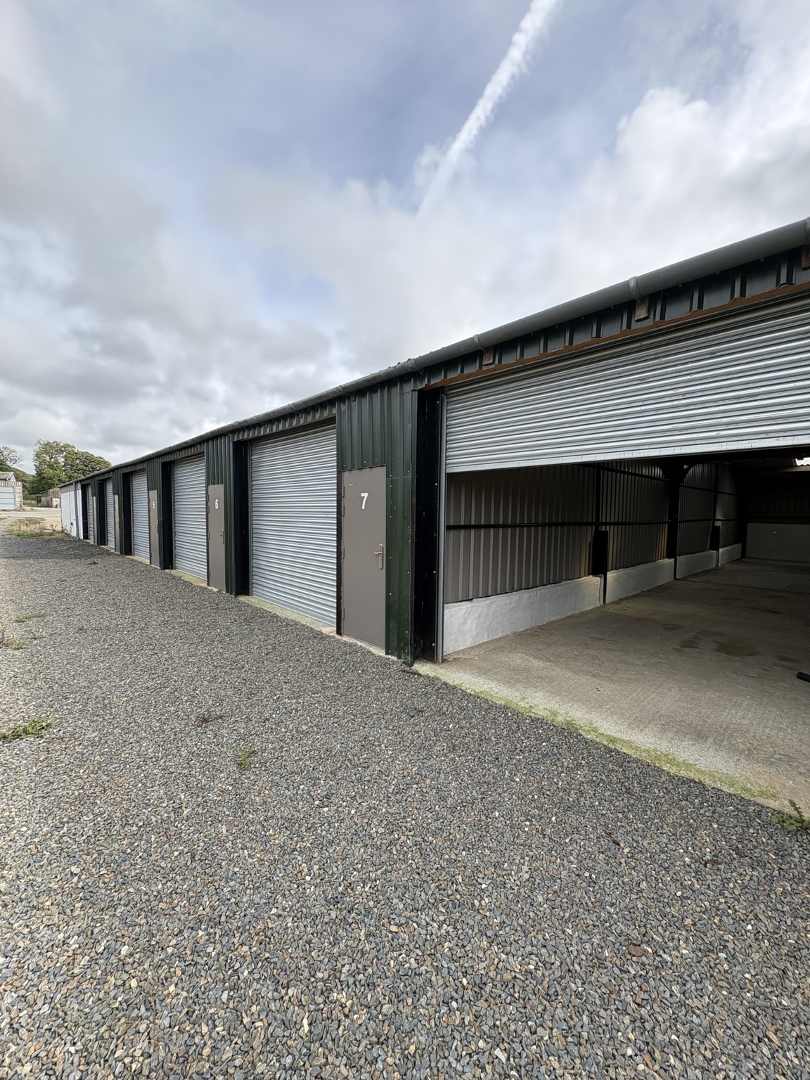 Summerton storage units with an open roller shutter and gravel area outside